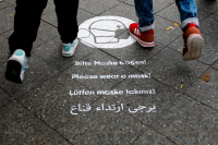 Tyske fotgjengere får en vennlig påminnelse om å bruke munnbind på fortauet i Karl-Marx-Strasse i Berlin.