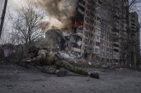 En ukrainsk politimann søker dekning foran en brennende bygning i Avdijivka i Ukraina i 2023.